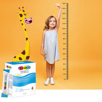 PEDIAKID Calcium C+ stickuri - fetiță care își măsoară înălțimea lângă o girafă-taliometru, alături de cutia de stickuri
