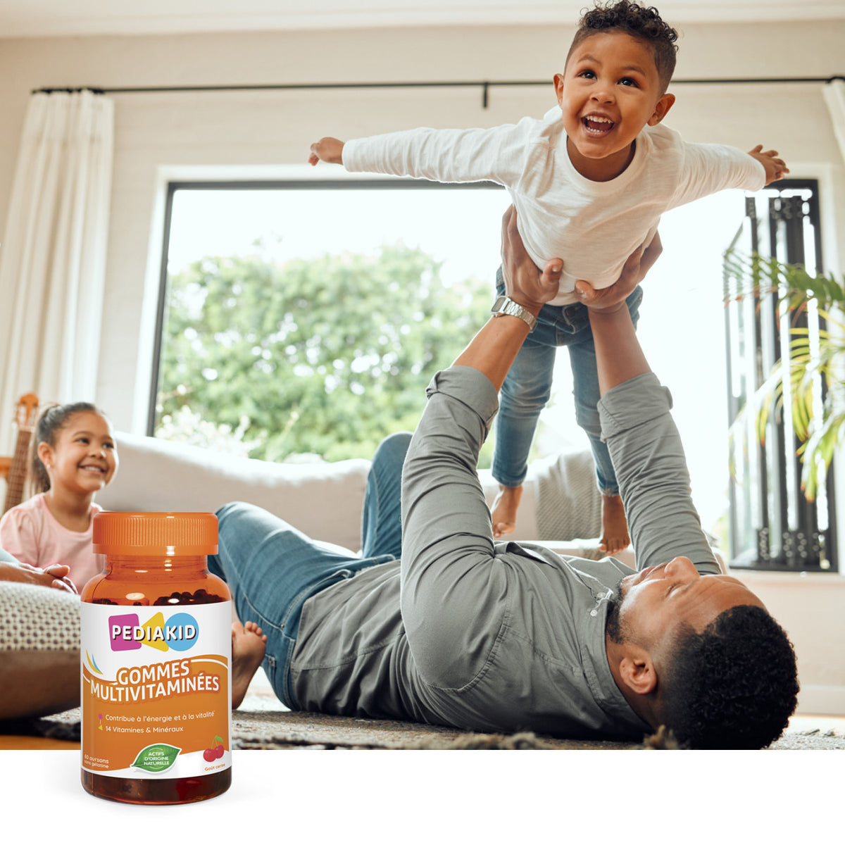 PEDIAKID Multivitamine ursuleți gumați - tată care se joacă acasă cu copilul, alături de flaconul de 60 de ursuleți
